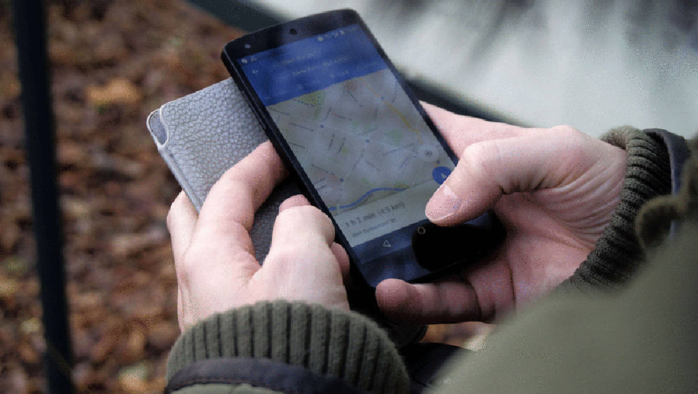 手握手机，屏幕上显示地图，灰色手机壳