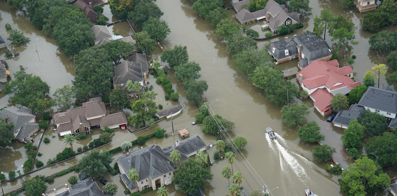 一个严重被洪水淹没的社区的鸟瞰图。一艘船正沿着过去的街道行驶。